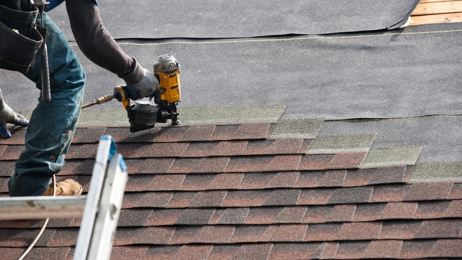 Asphalt shingles fastened by a roofer using a pneumatic coil nailer
